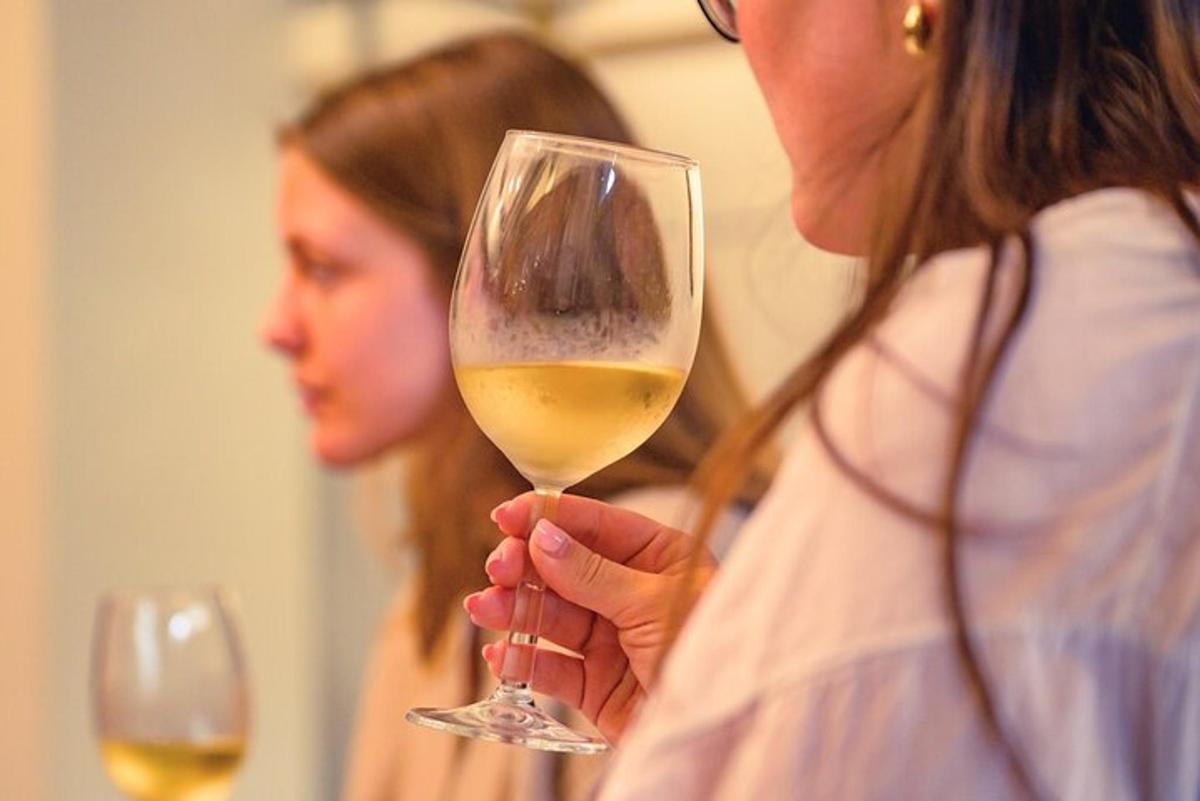 una donna che tiene in mano un bicchiere di vino bianco