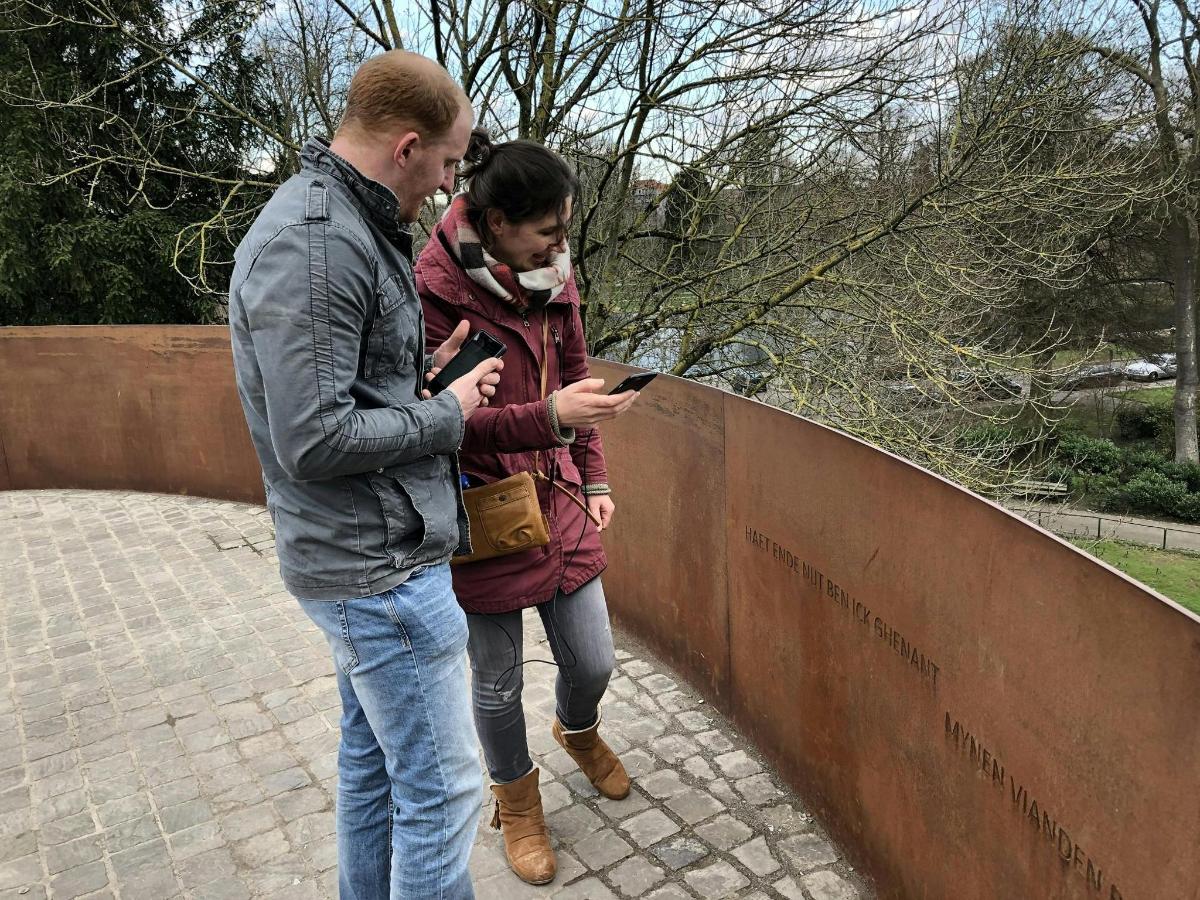 egy férfi és egy nő nézi a mobiltelefonját