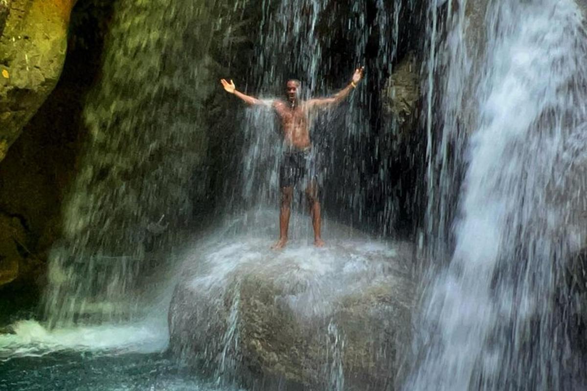 un home dret sobre una roca sota una cascada