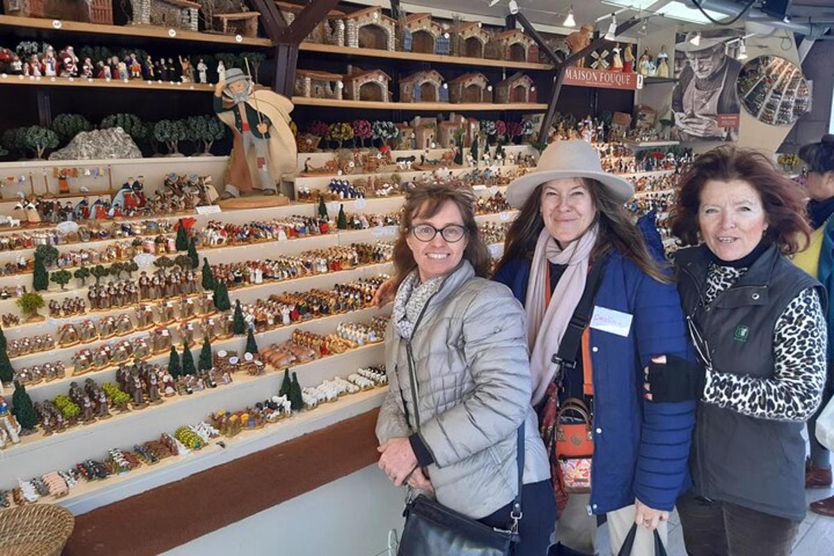 trei femei stând în fața unui expoziție de figurine