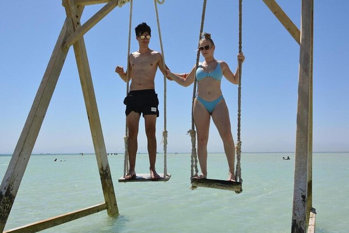 seorang lelaki dan seorang wanita duduk di atas buaian di pantai