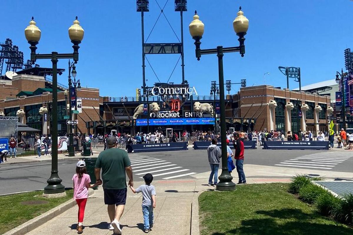 Un grupo de personas caminando frente a un estadio de béisbol.
