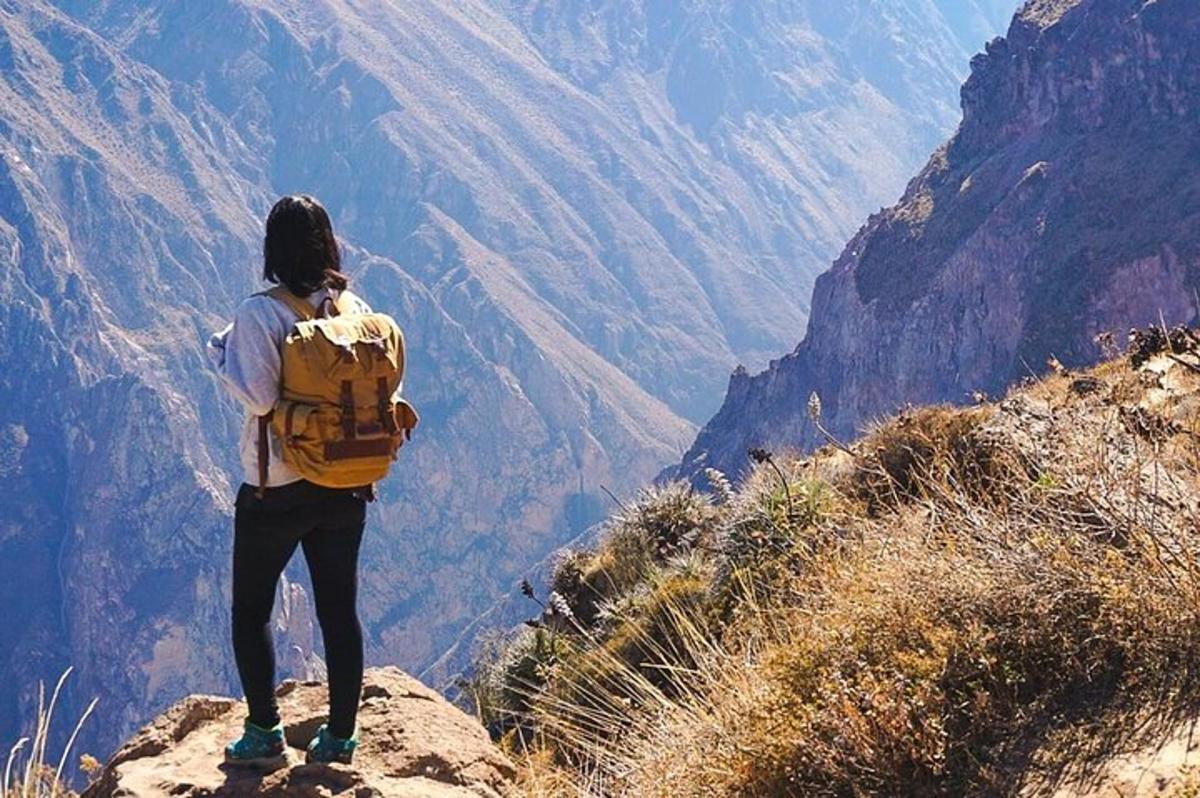 una persona con uno zaino in piedi sulla cima di una montagna