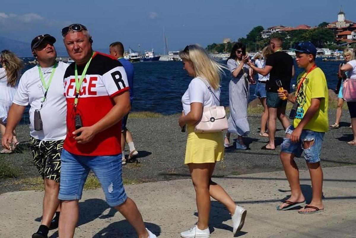 a group of people standing on a sidewalk near the water