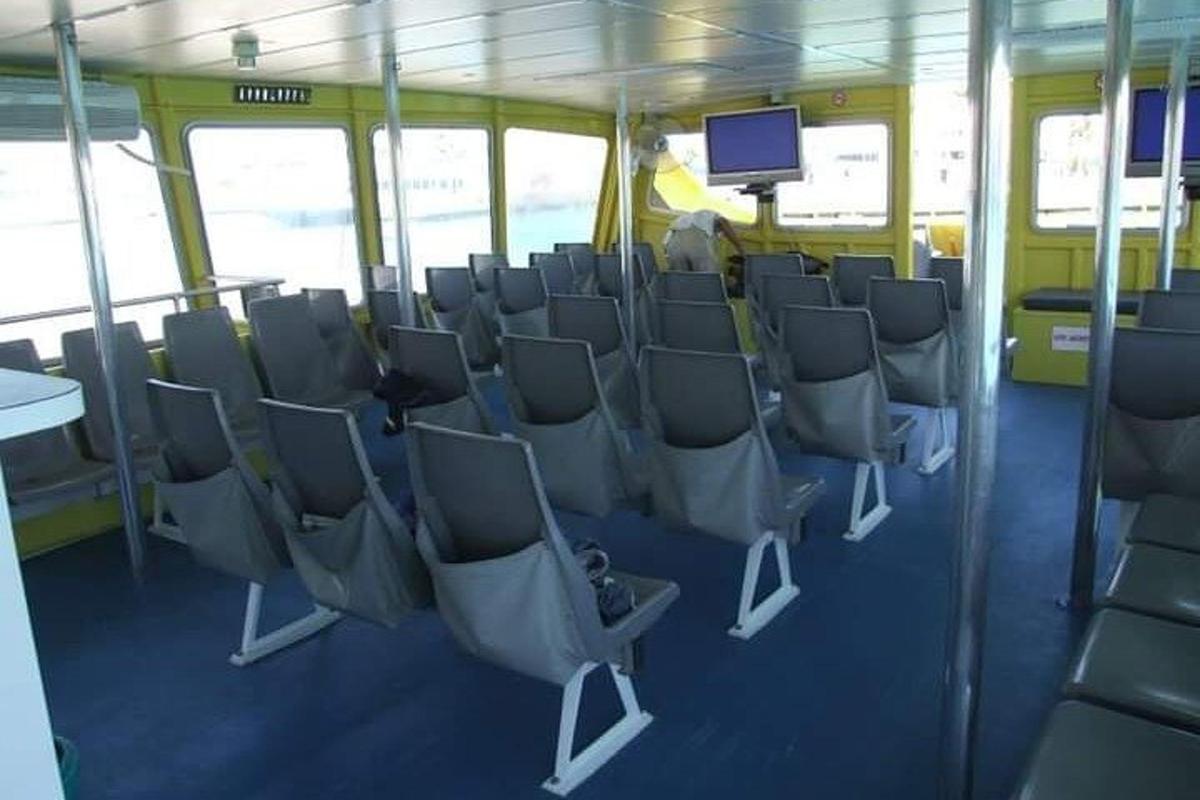 Un autobús con filas de sillas y un televisor encima.