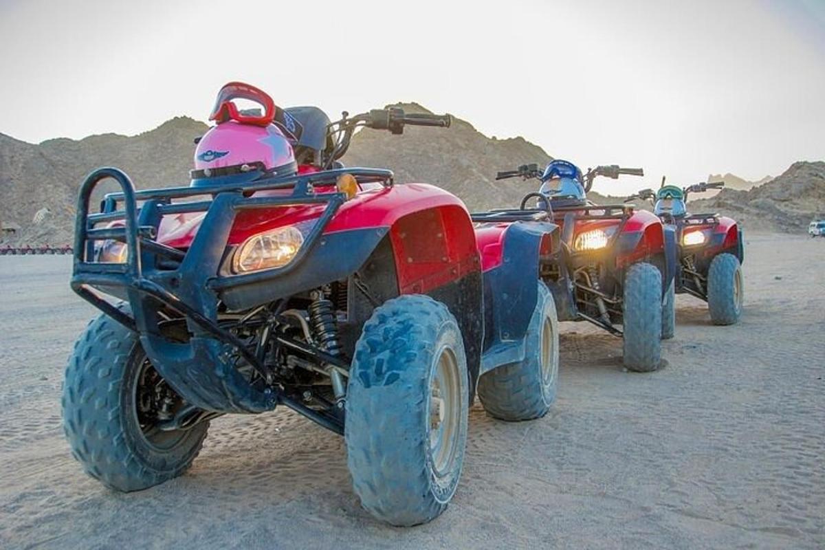 Dos vehículos de cuatro ruedas y un casco rosa en la playa