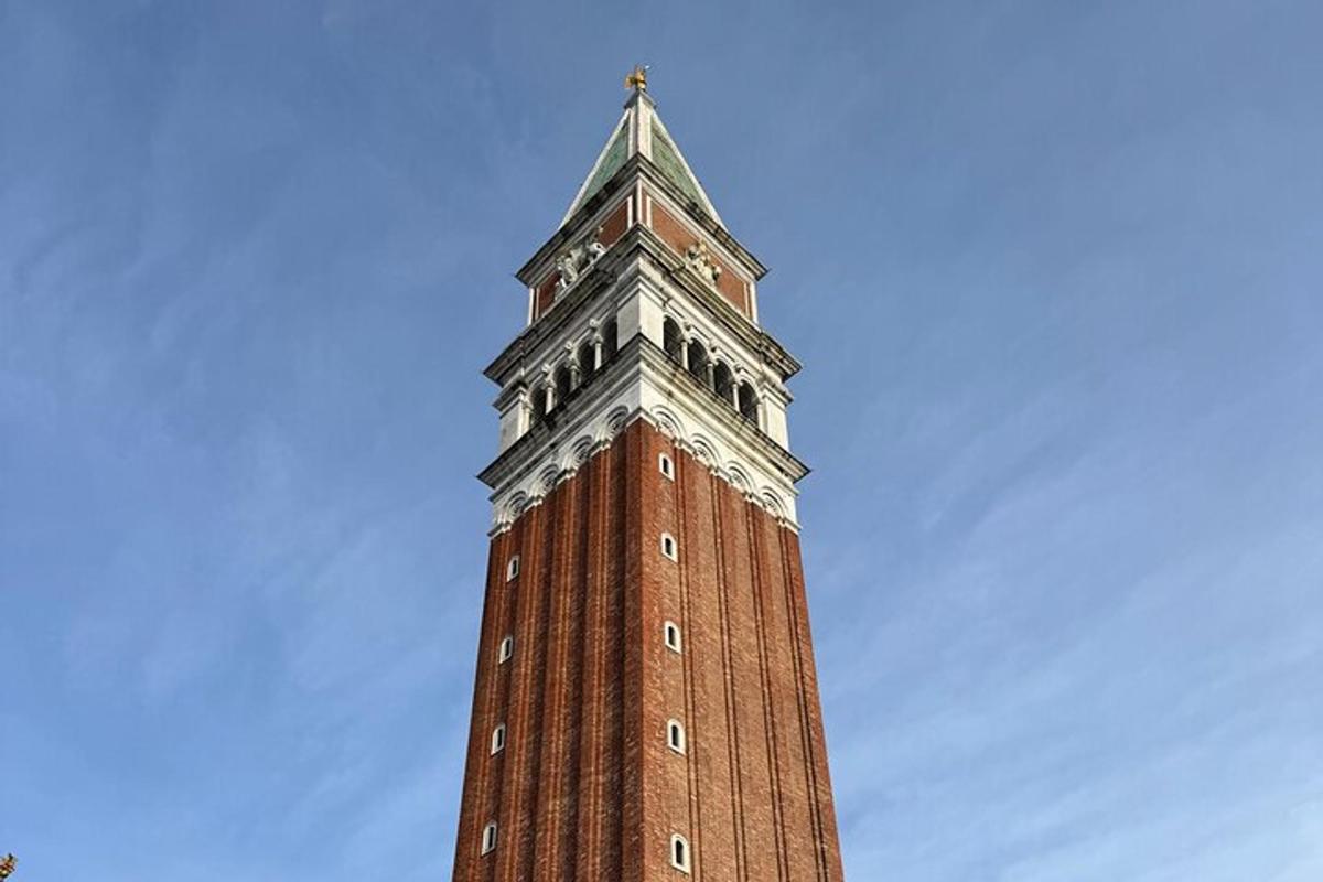 a tall brick clock tower with a cross on top