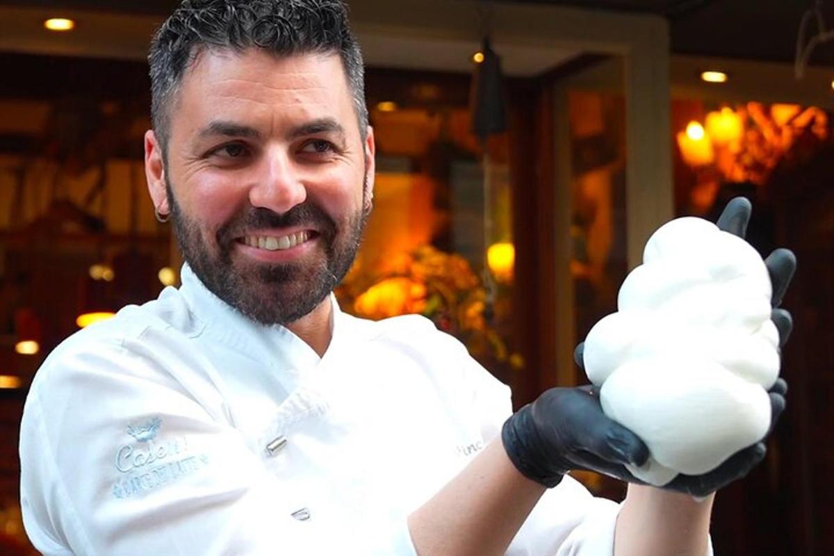 seorang lelaki berpakaian chef putih memegang sebiji bola makanan