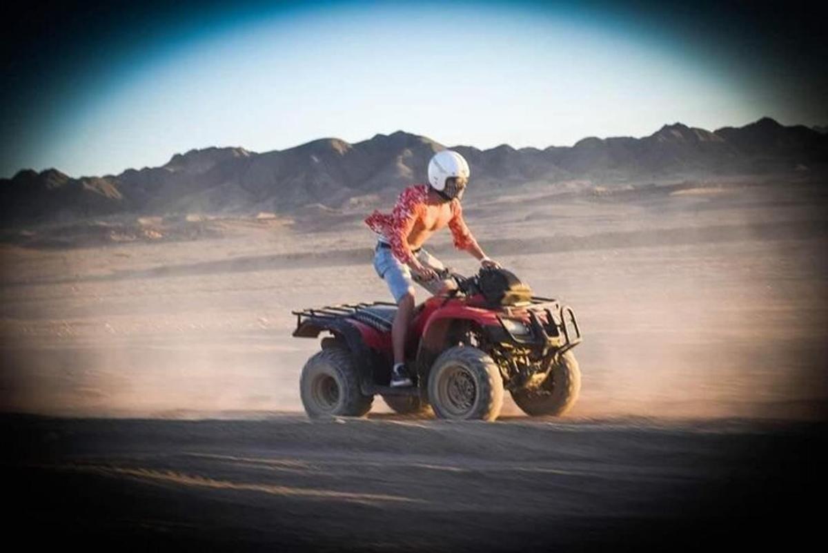 una persona que condueix un quad al desert