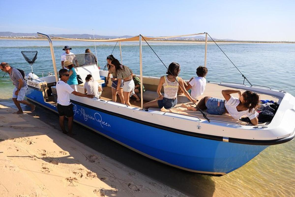 sekumpulan orang di atas bot biru di pantai
