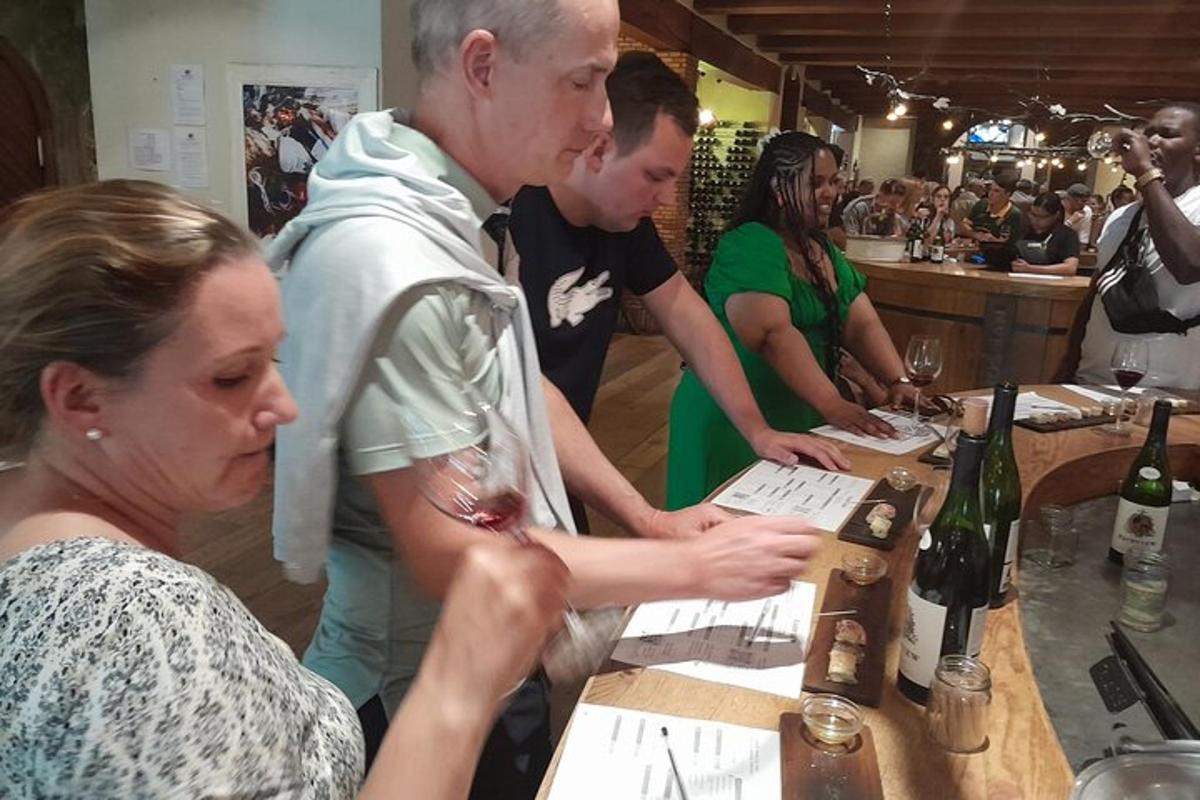 un gruppo di persone in piedi al bar con bottiglie di vino