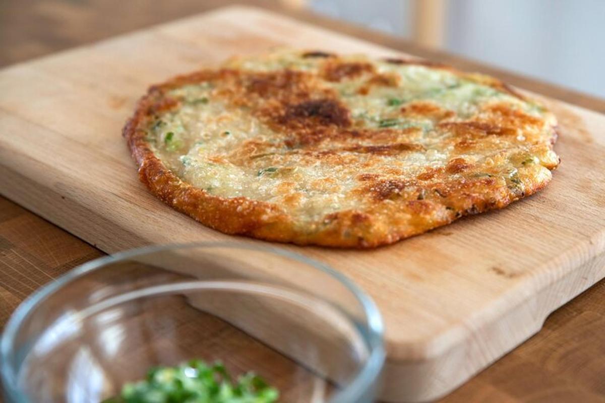een pizza op een houten snijplank naast een kopje