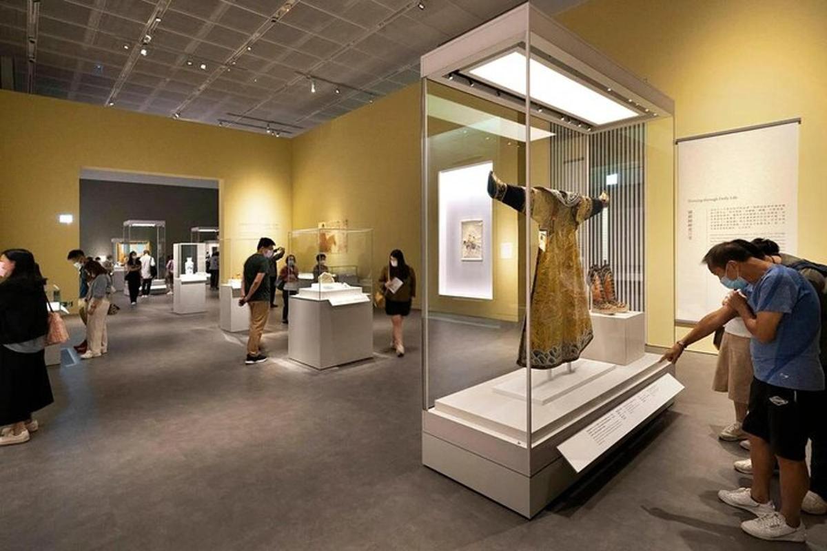 a group of people looking at a dress on display in a museum