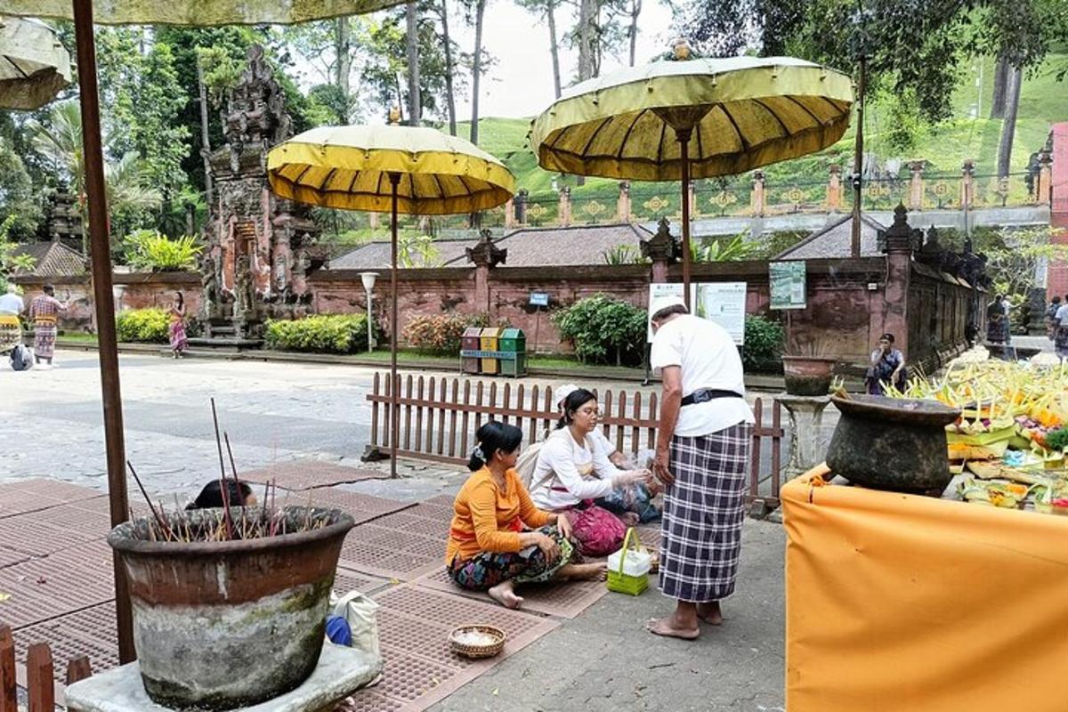 sekumpulan orang duduk di atas tanah di bawah payung