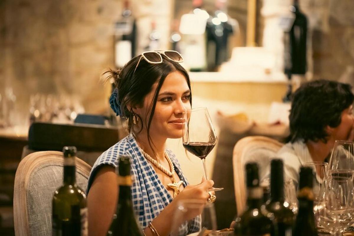 ženska, ki sedi za mizo s kozarcem vina