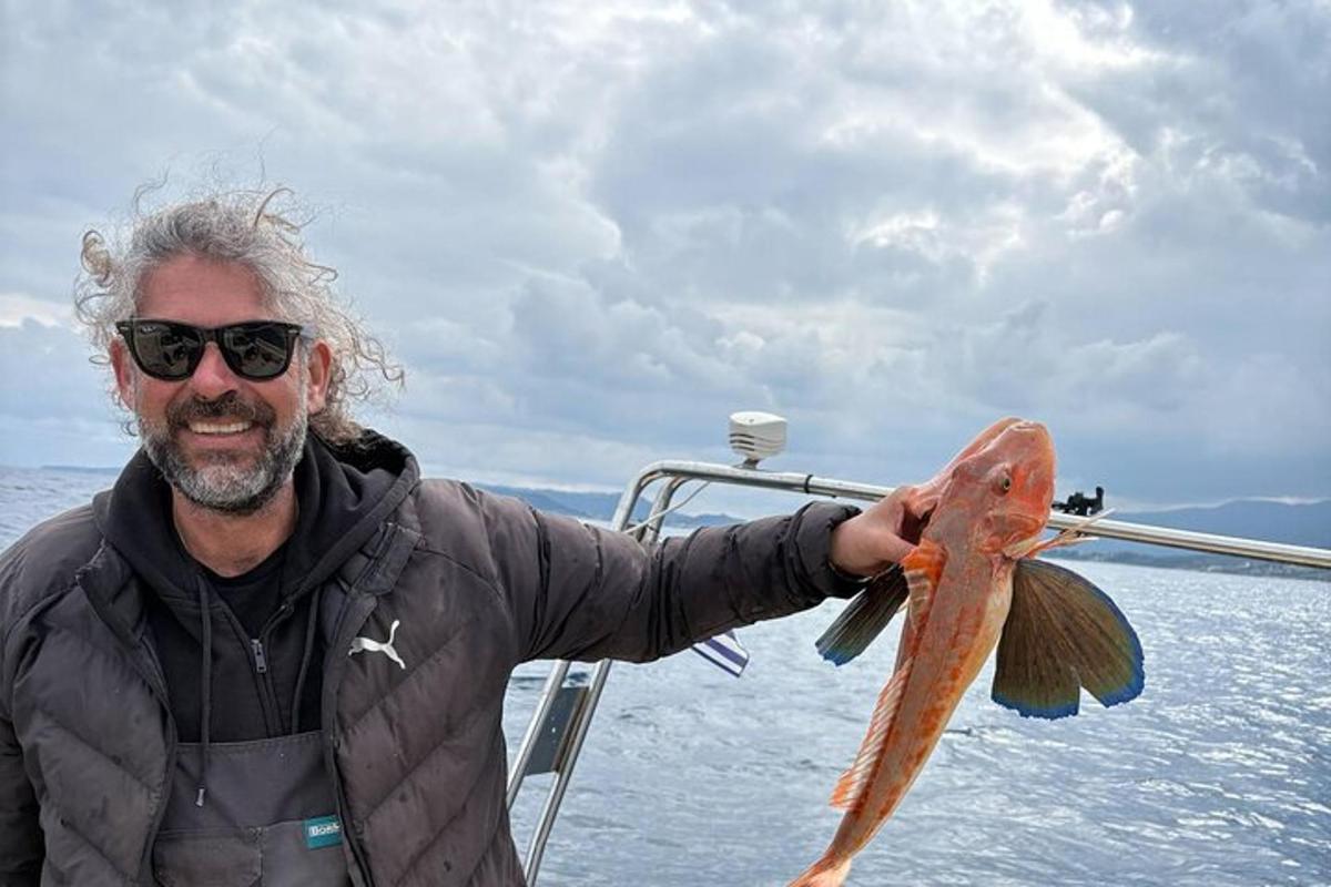 um homem segurando um peixe na mão em um barco
