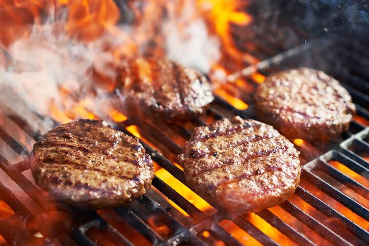 eine Gruppe von Hamburgern, die auf einem Grill kochen