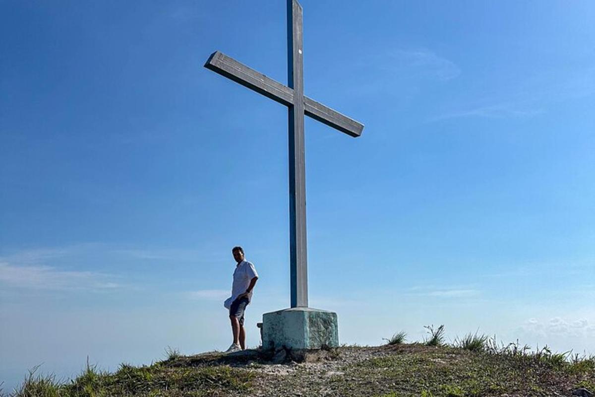 moški, ki stoji ob križu na hribu
