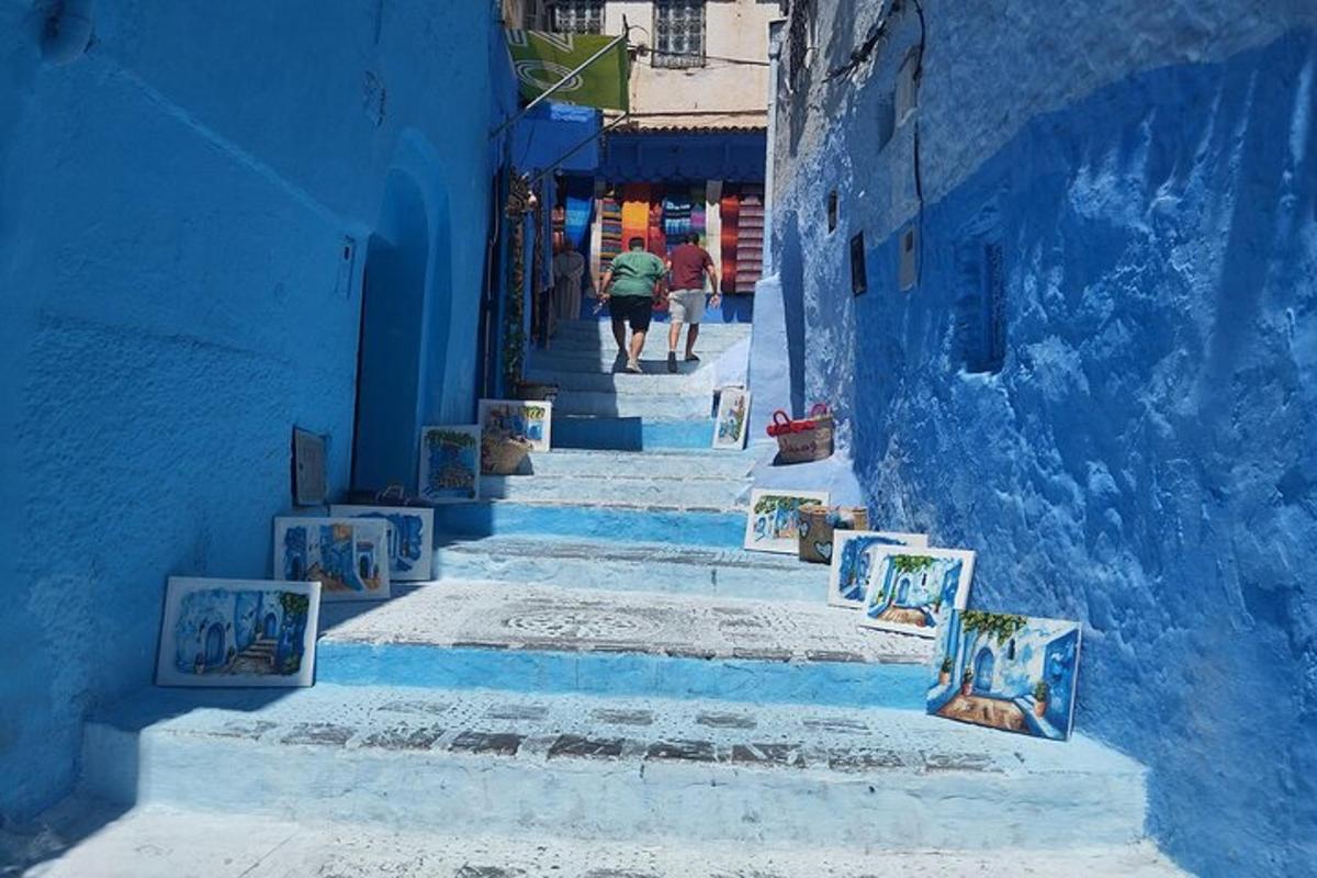 a blue alley with stairs with paintings on them