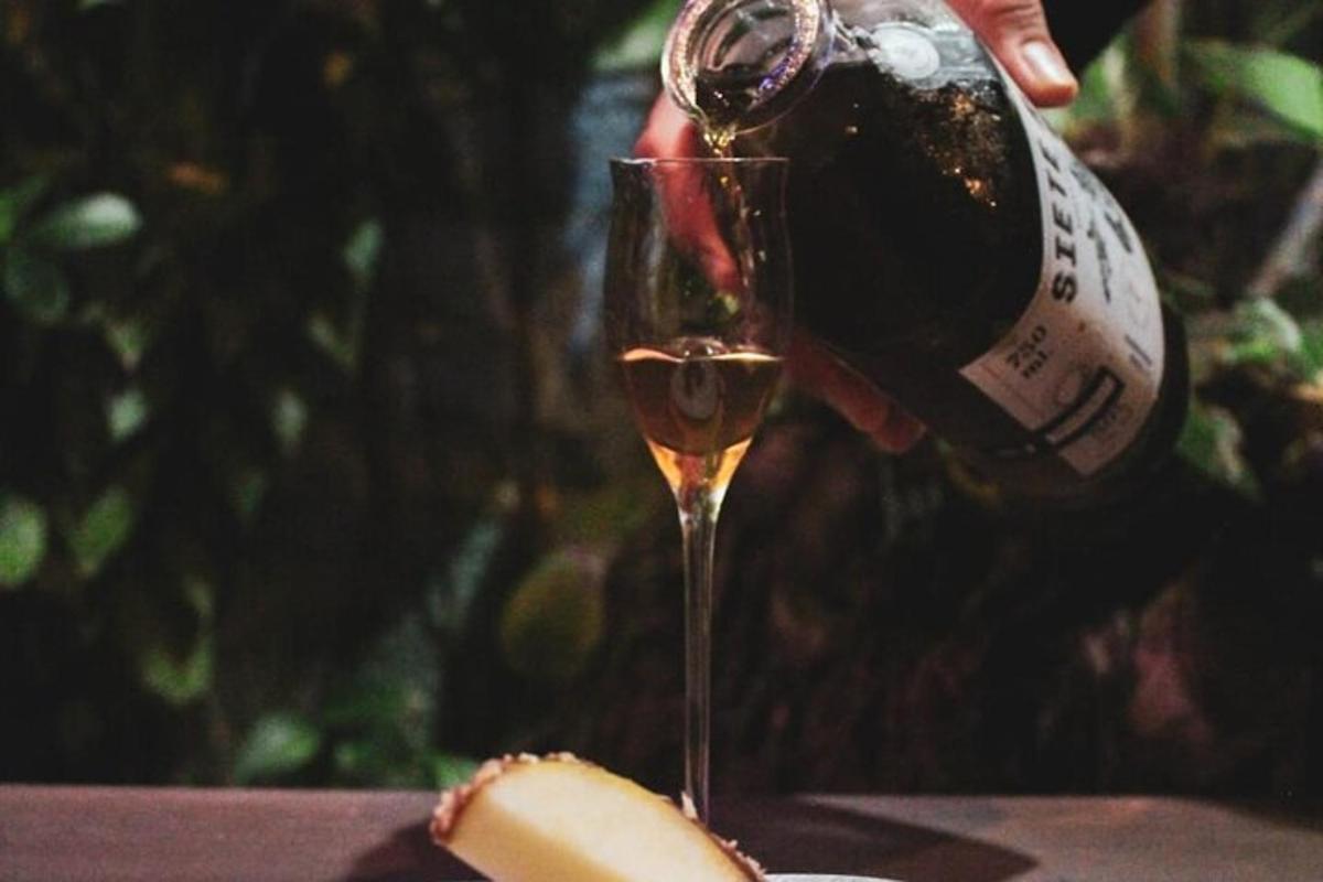 una persona che versa una bottiglia di vino in un bicchiere da vino