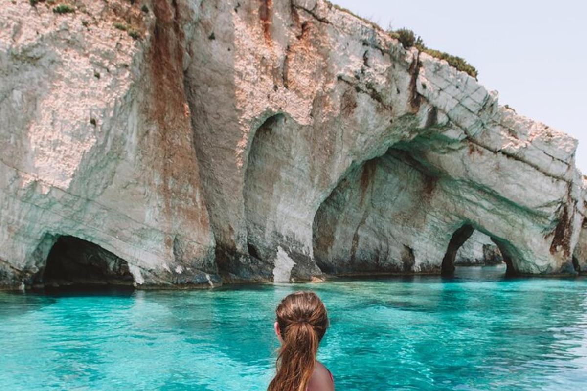 Una mujer sentada en el agua frente a una cueva.
