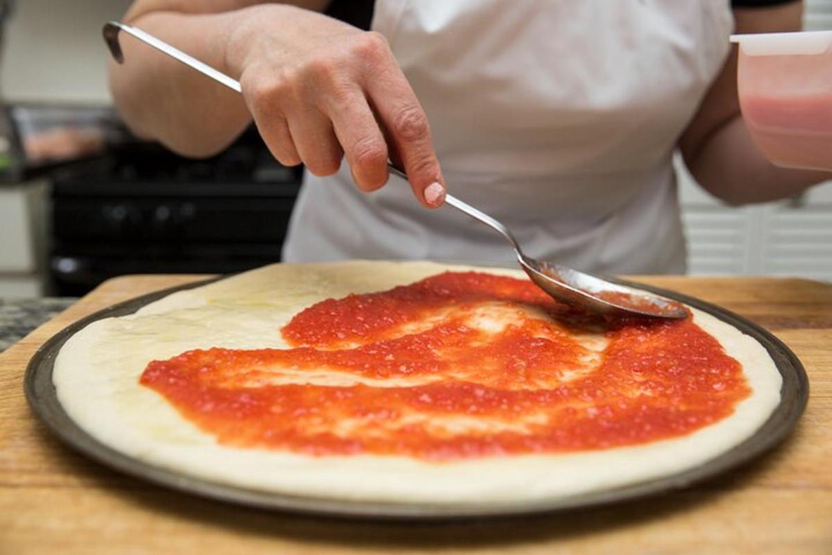 a person holding a knife and fork over a pizza