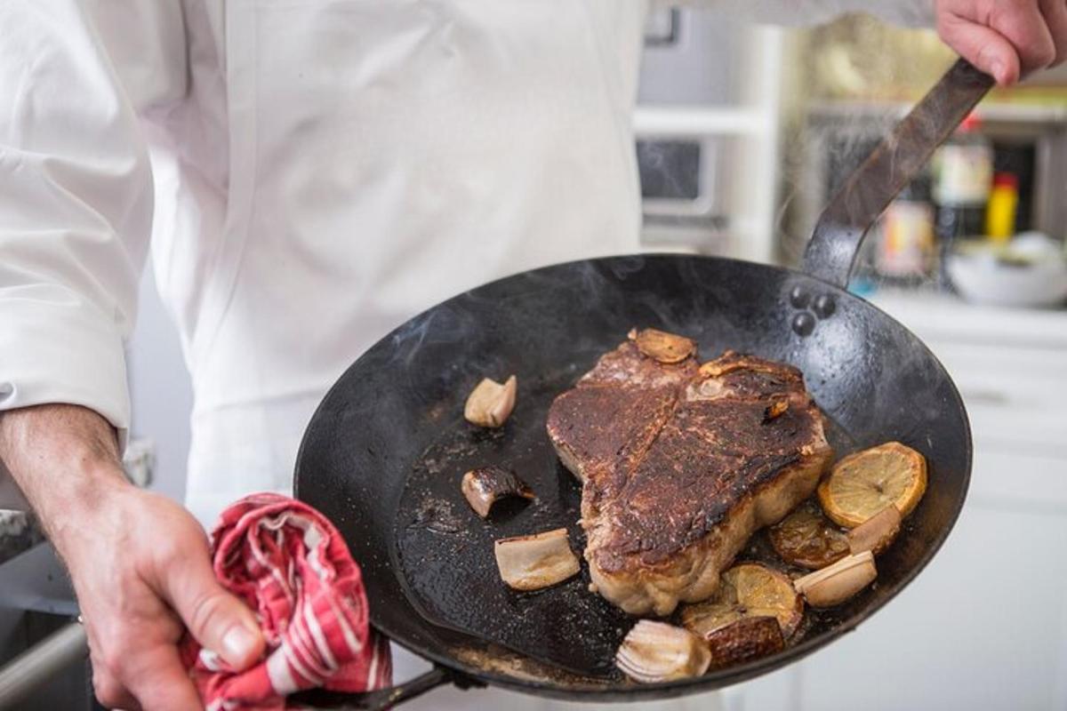 un home que sosté una paella amb un tros de carn a sobre