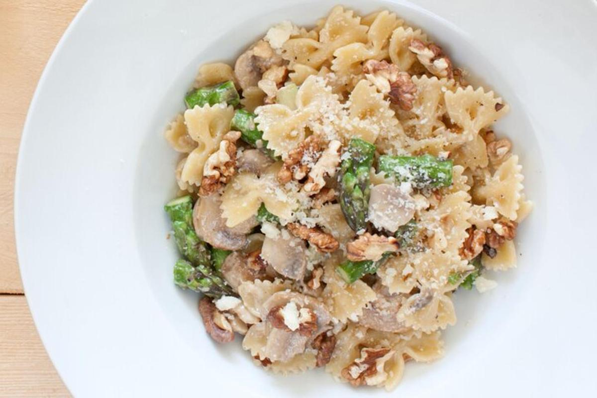 una ciotola bianca di pasta e verdure su un piatto