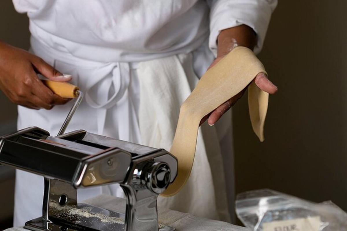 un uomo tiene in mano un pezzo di pasta accanto a una macchina da cucire
