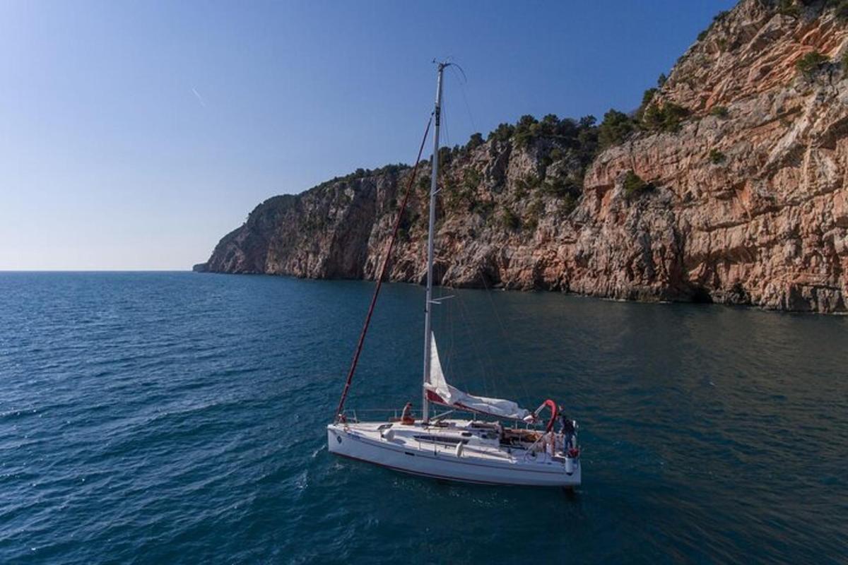 μια άσπρη βάρκα στο νερό δίπλα σε έναν απότομο βράχο