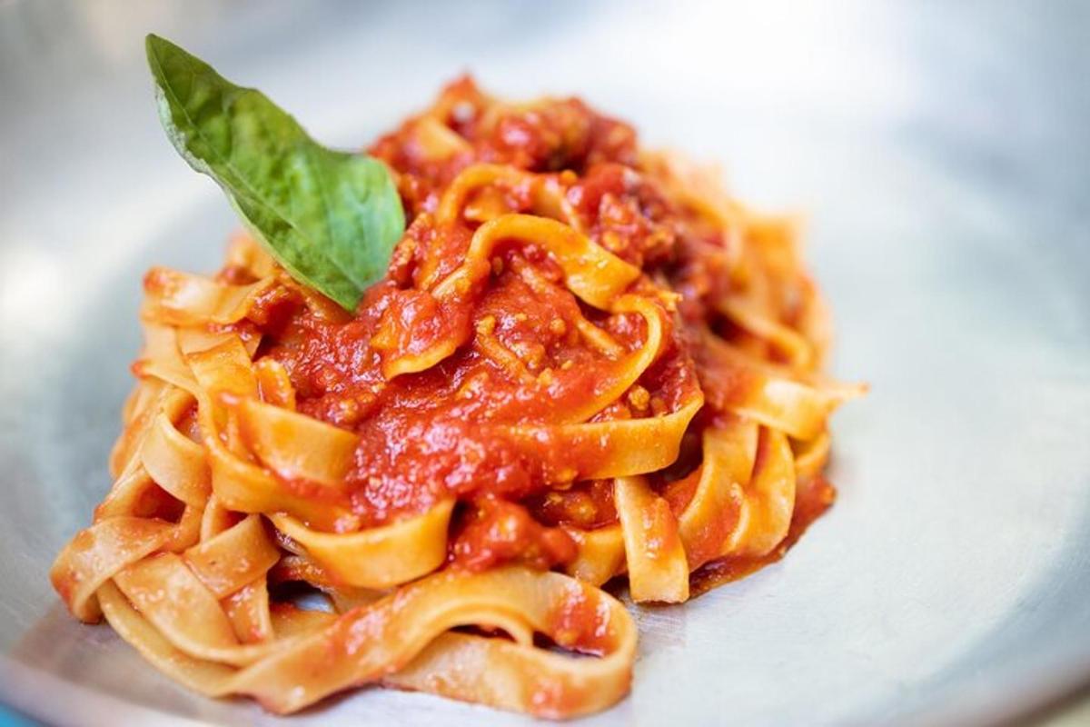 um prato de macarrão com molho de tomate e uma folha verde