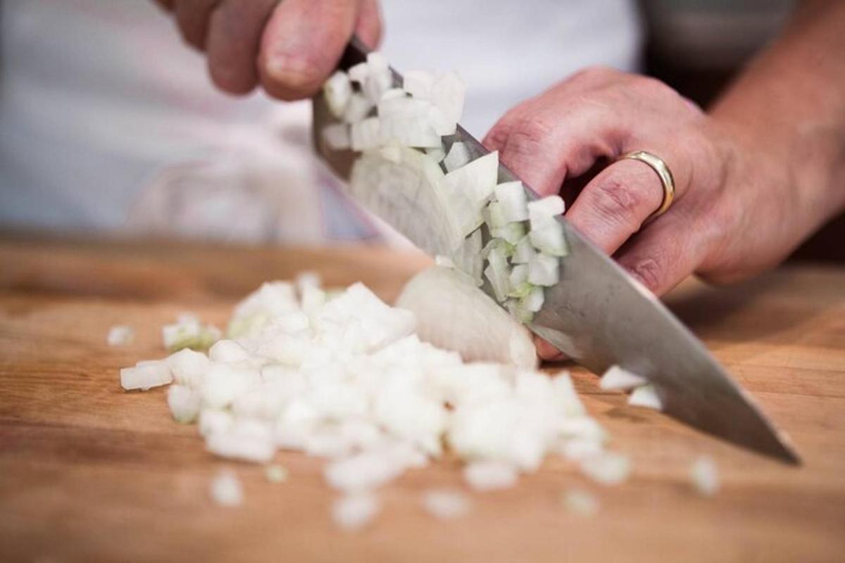 una persona che taglia le cipolle su un tagliere con un coltello