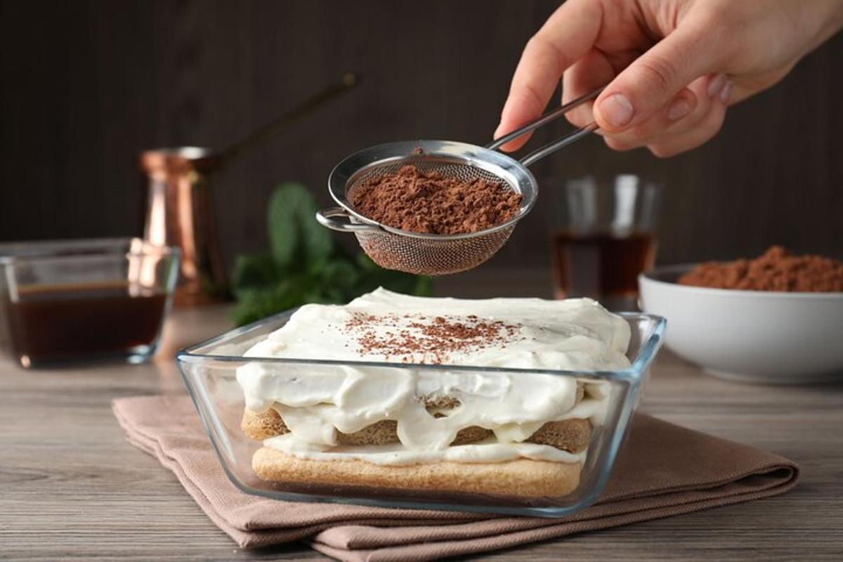 eine Person, die Essen in eine Glasschale mit einem Dessert löffelt