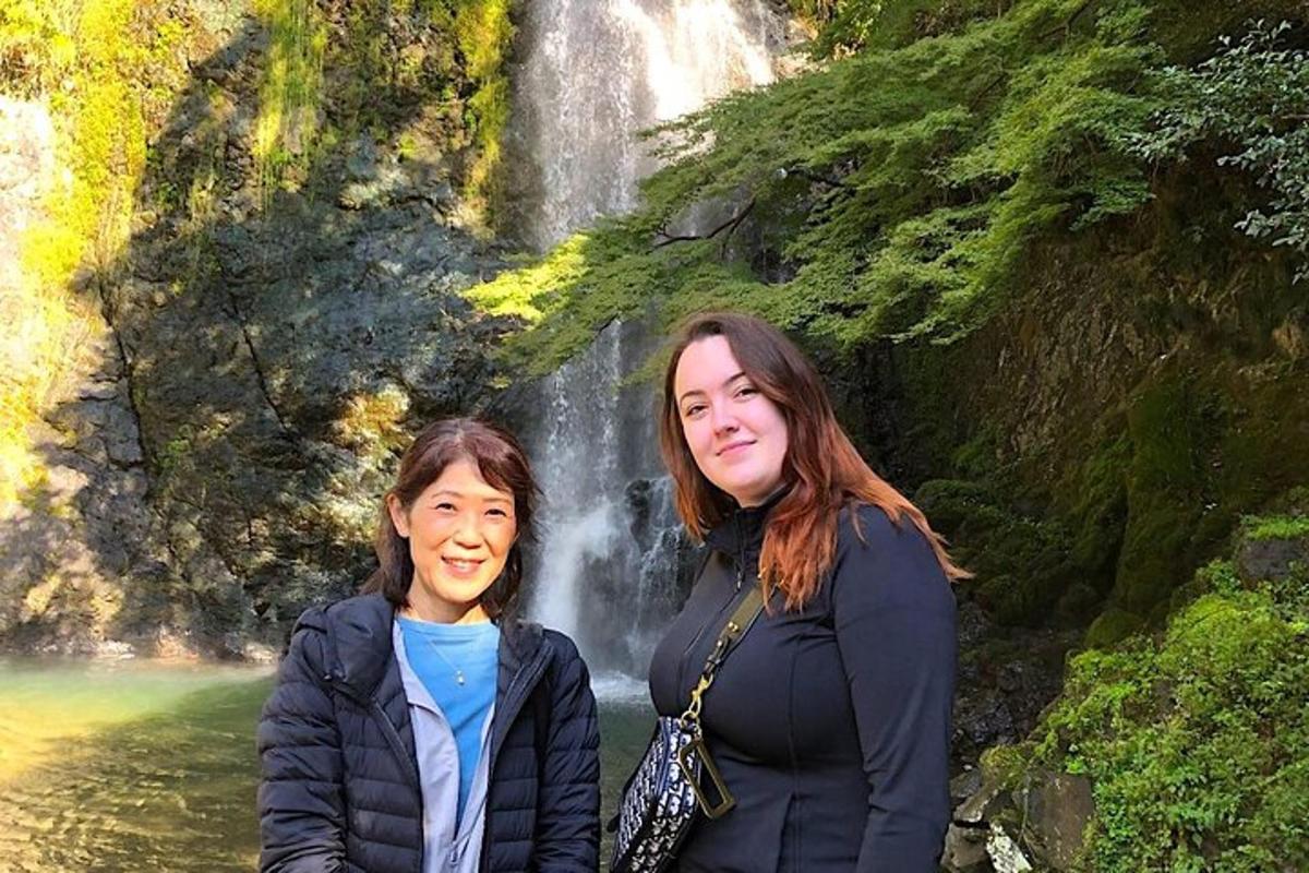 dua wanita berdiri di hadapan air terjun