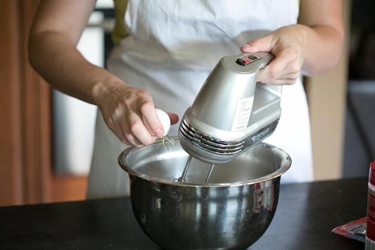 una persona che usa un mixer in una ciotola di metallo