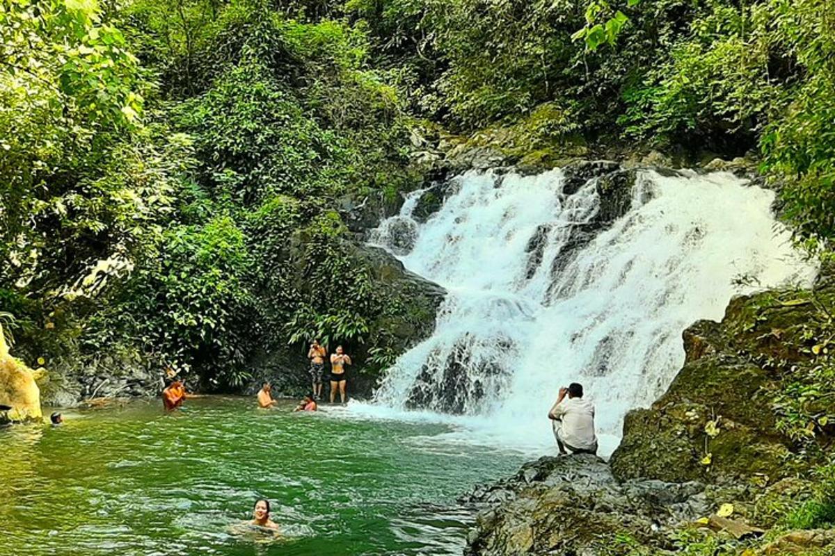 a group of people in the water near a waterfall