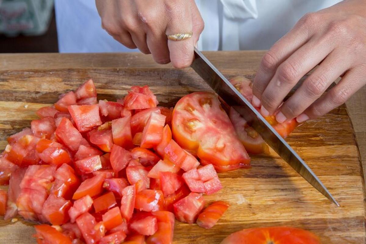 osoba krájející rajčata na prkénku nožem