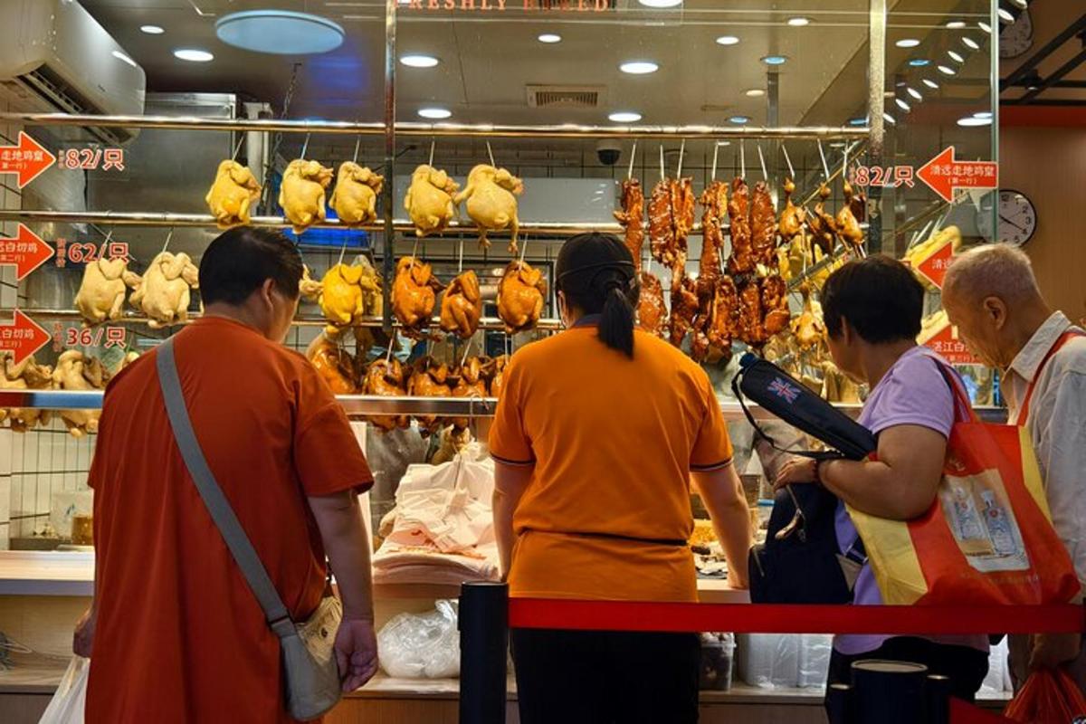 a group of people standing in a store looking at chickens