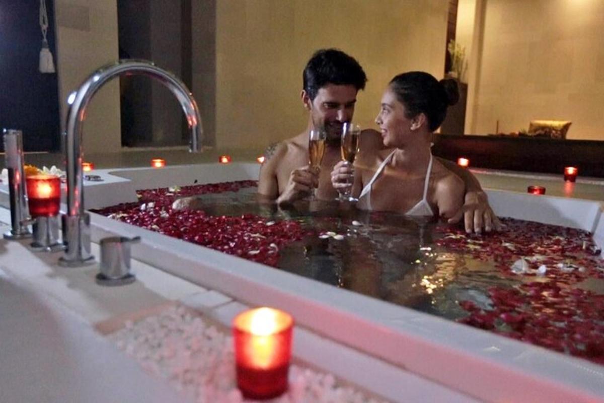 seorang pria dan wanita minum sampanye di bak mandi