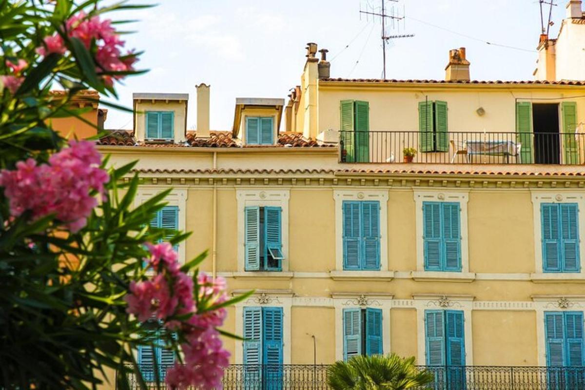 ein Gebäude mit blauen Fensterläden und rosa Blumen