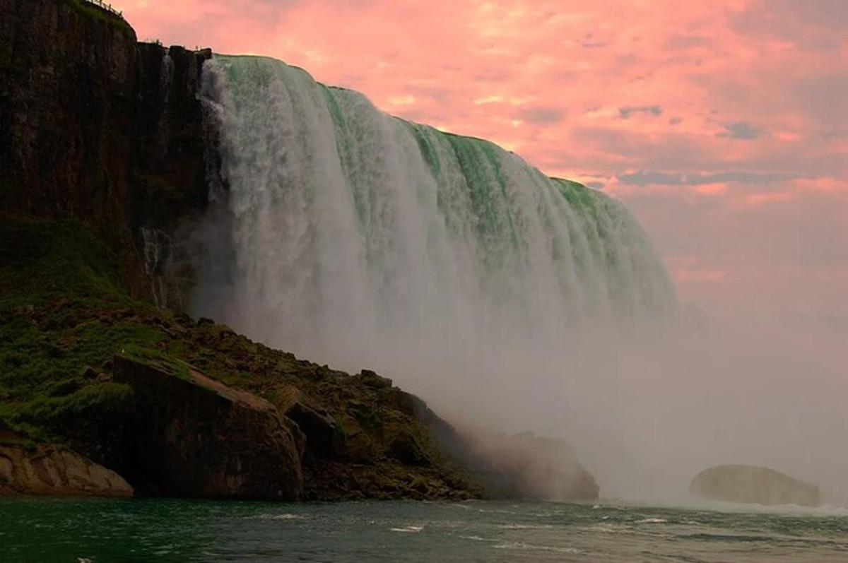 a waterfall on the side of a mountain with a cloudy sky