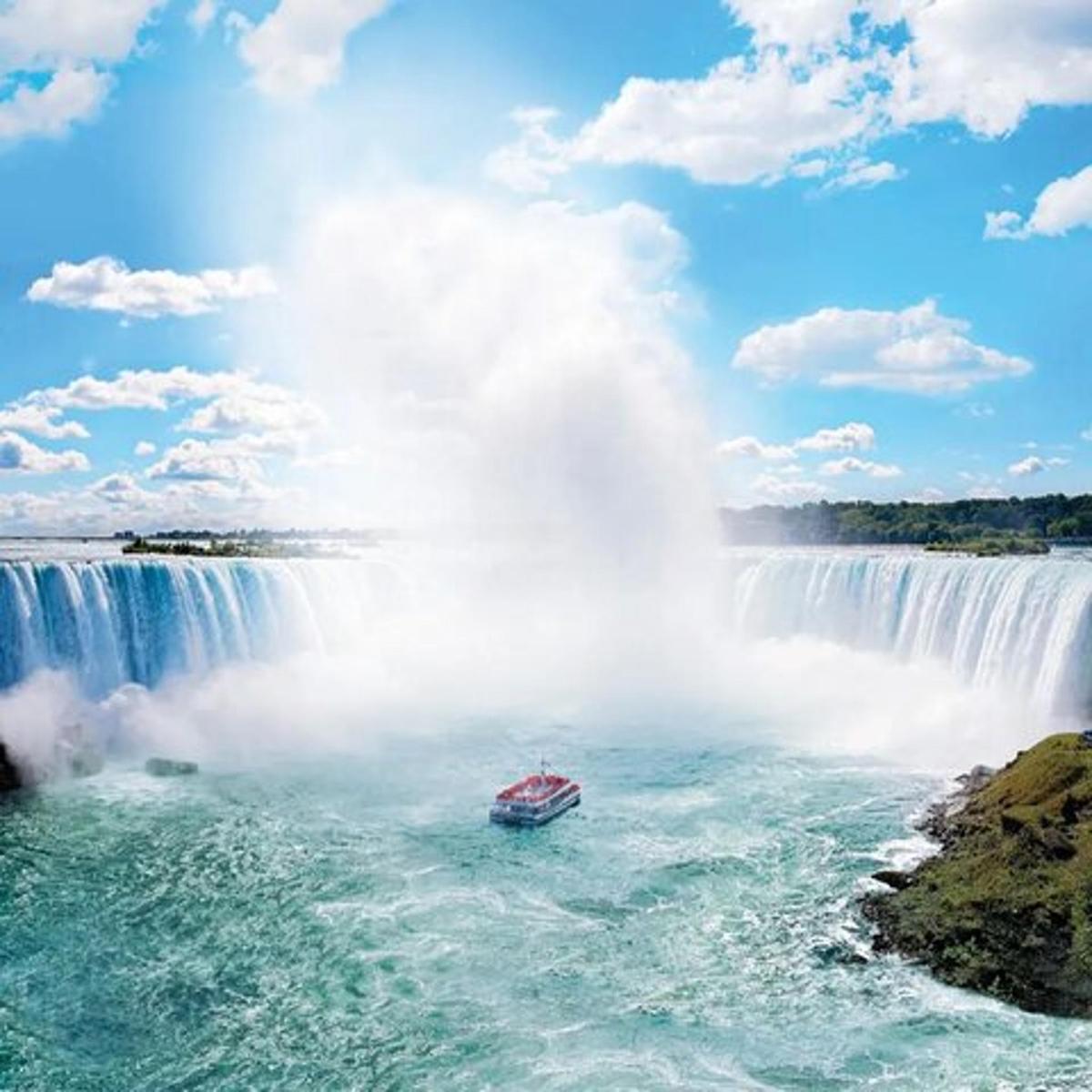 a boat in the water in front of a waterfall