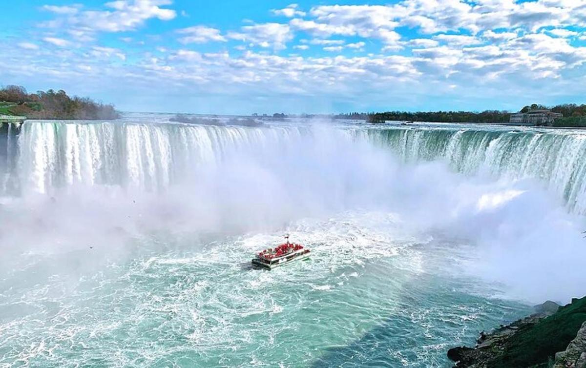 a boat in the water in front of a waterfall