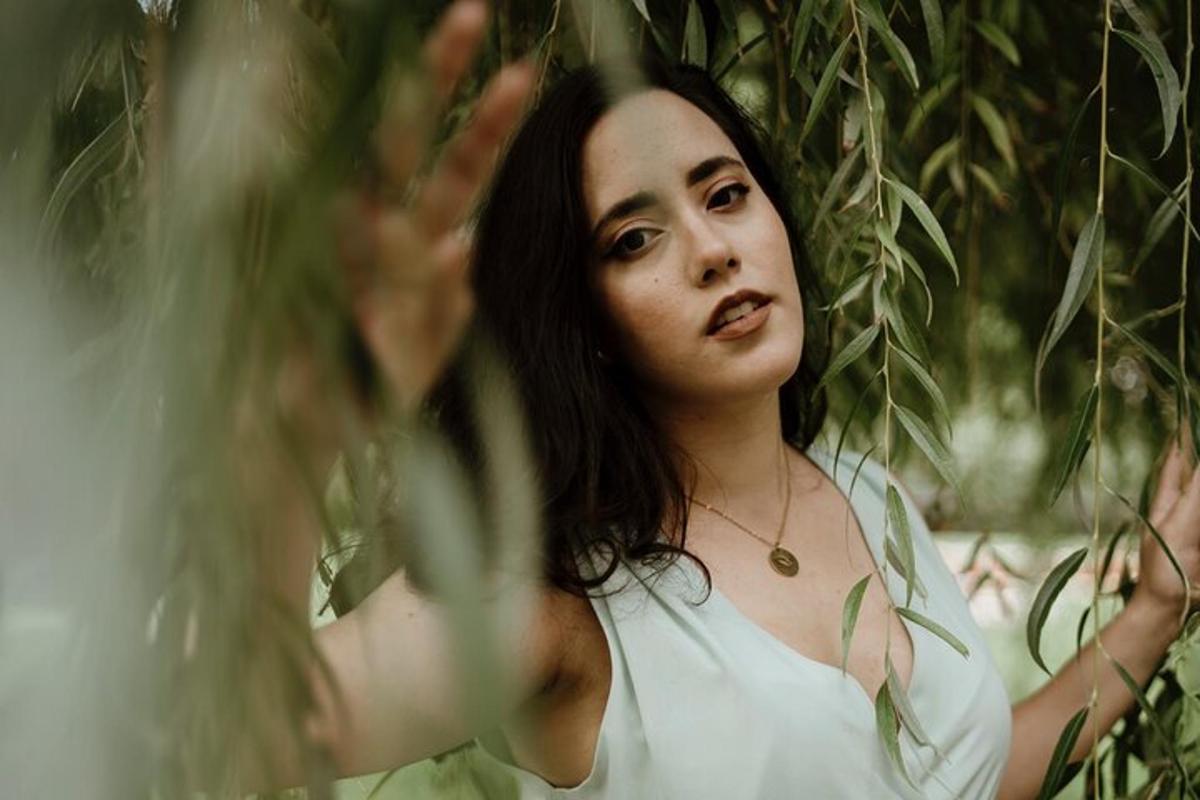 a woman in a white dress standing under a tree