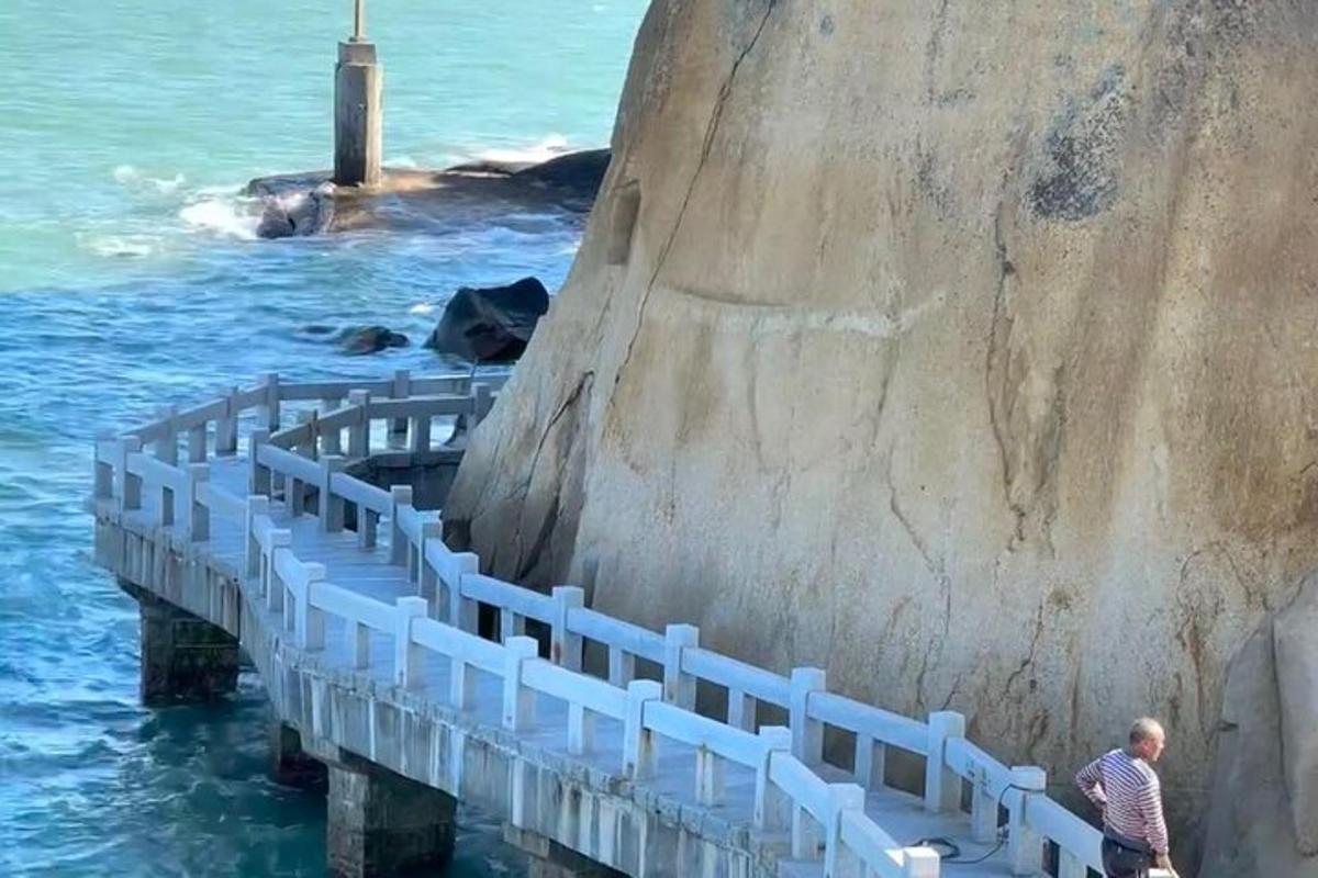 a man walking on a pier next to the ocean