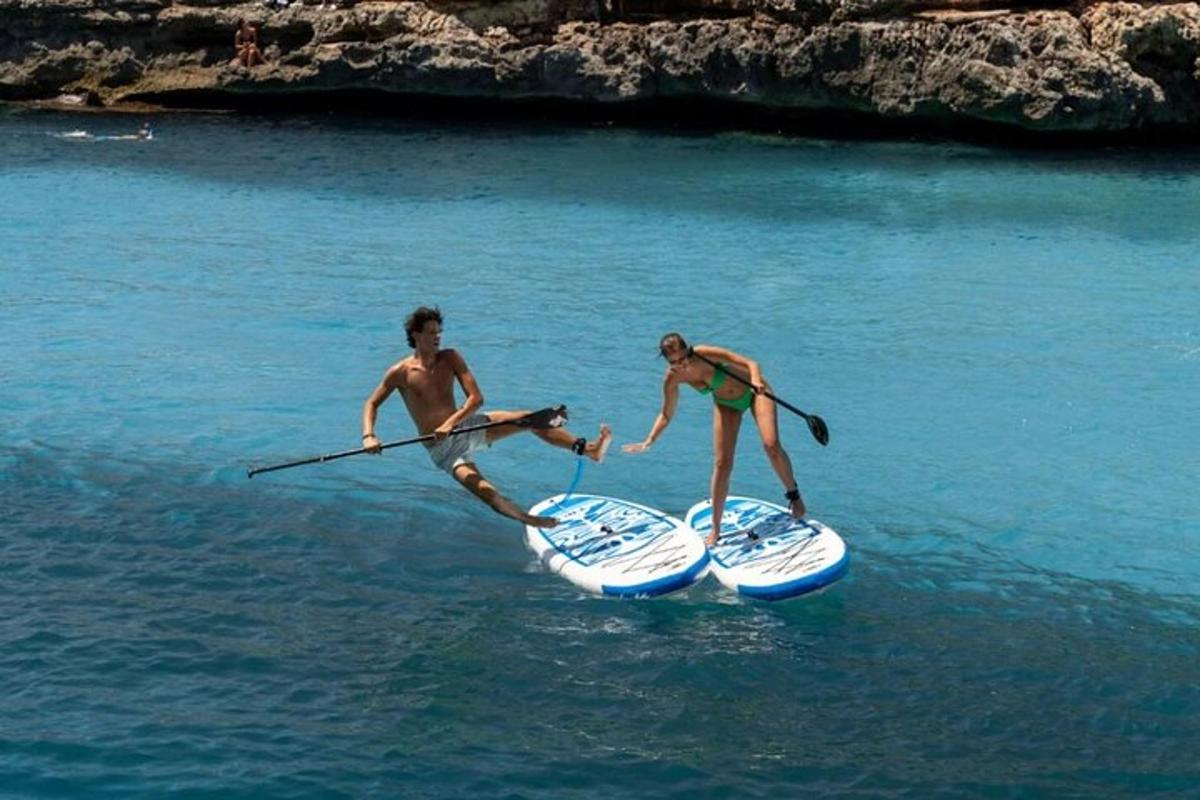 divi cilvēki stāv uz SUP dēļiem ūdenī