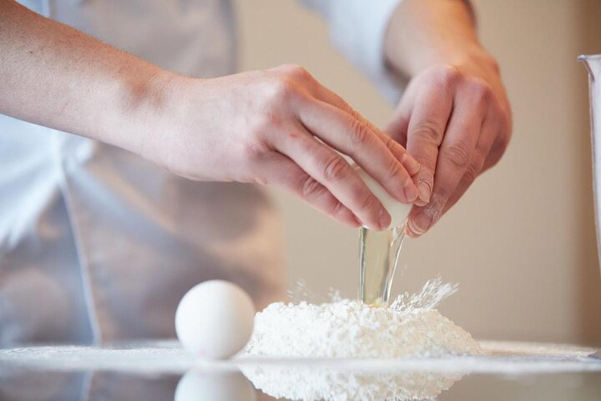 osoba pridávajúca ingrediencie do kopy múky