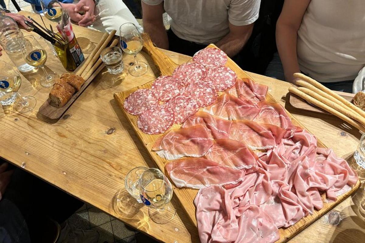 Una mesa de madera cubierta con carne y copas de vino.
