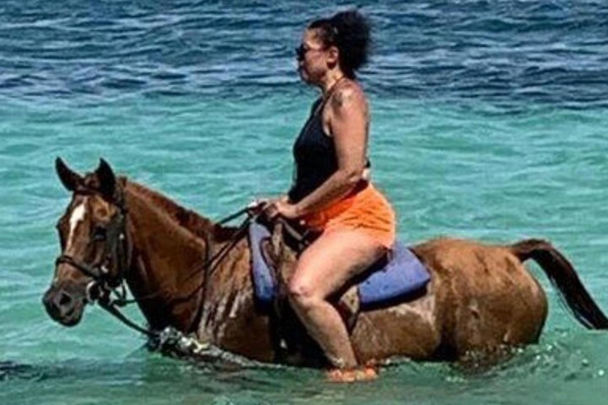 μια γυναίκα που καβαλάει ένα άλογο στον ωκεανό