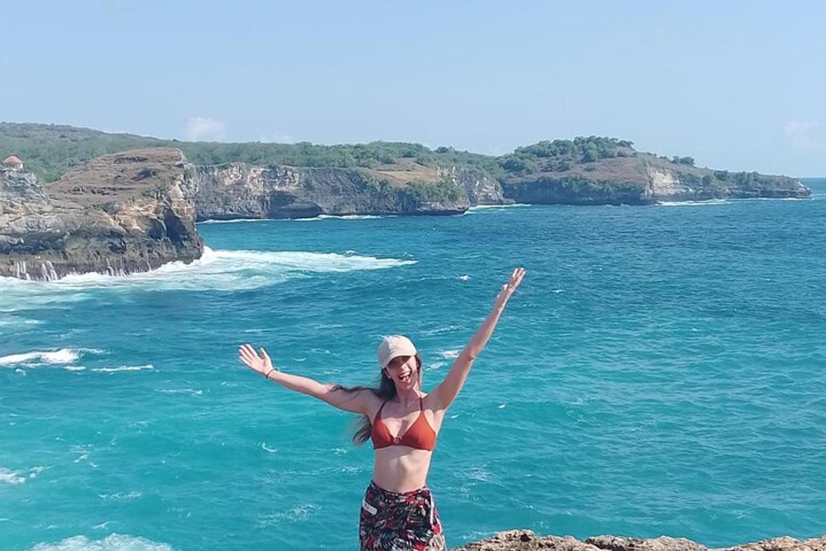 una donna in bikini in piedi su una scogliera vicino all'oceano